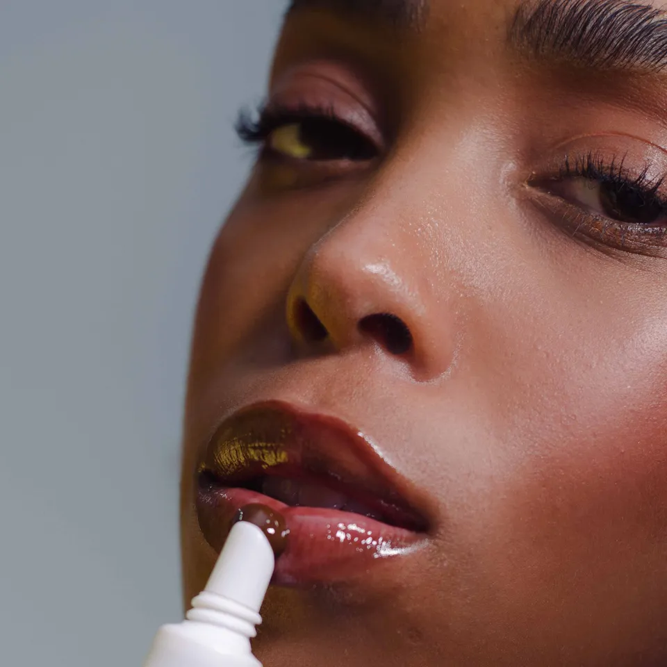 Modelo aplicando o Lip Gloss nos lábios